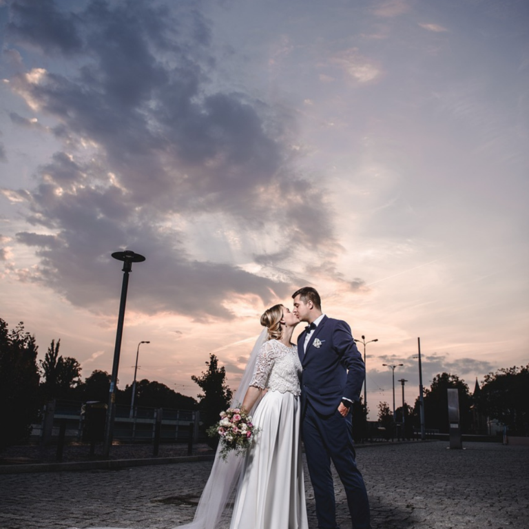 Picturesque wedding photoshoot with grey skies at dusk, bride and groom celebrating with a romantic kiss