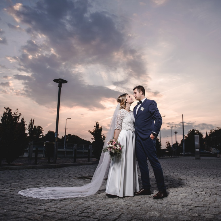 Picturesque wedding photoshoot with grey skies at dusk, bride and groom looking into each other's eyes romantically