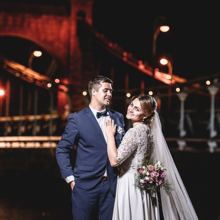 Picturesque wedding photoshoot at night, the bride is looking into the camera, and the groom is looking at how beautiful the bride is