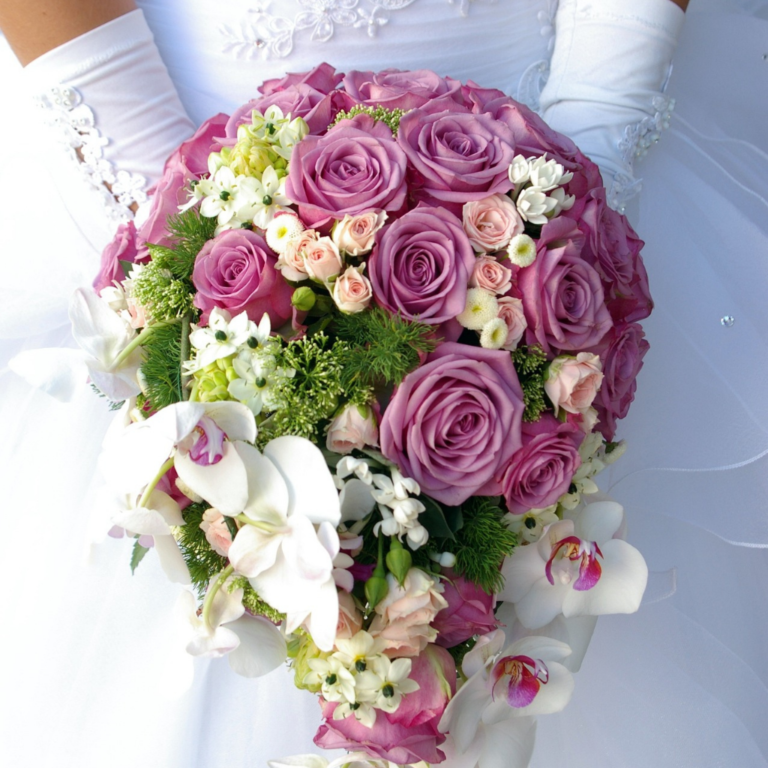 Wedding bouquet of pink roses, white orchids and other flower arrangements held by a bride in a white wedding gown