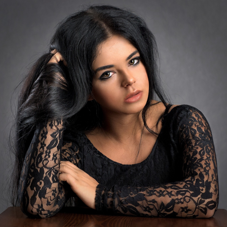 Personal studio portrait of a lady holding a lock of her hair and looking dead serious