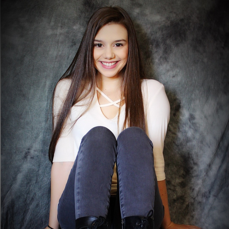 Personal studio portrait of a lady sitting on the floor, smiling and looking really happy