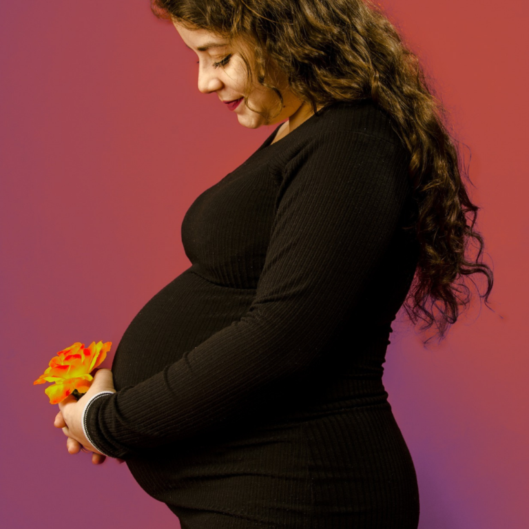 Maternity photoshoot of a pregnant woman in a black dress holding a yellow flower