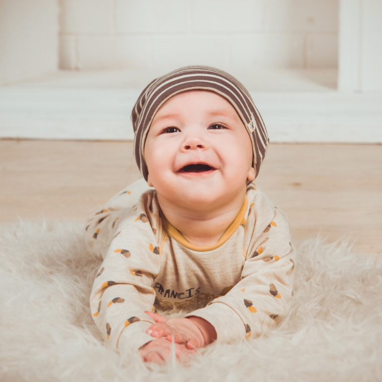 Studio photoshoot for a happy and smiling little child in Pyjamas and a head warmer cap