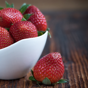 Product photoshoot, strawberries in a white bowl on a wooden table