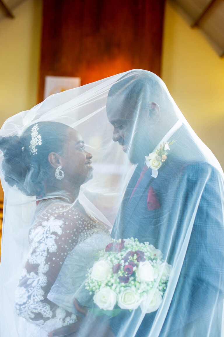 Wedding Shoot by Quintessence Photography UK with a Couple cuddled under the bride's veil